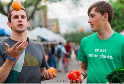 Two people holding fruits and vegetables talking