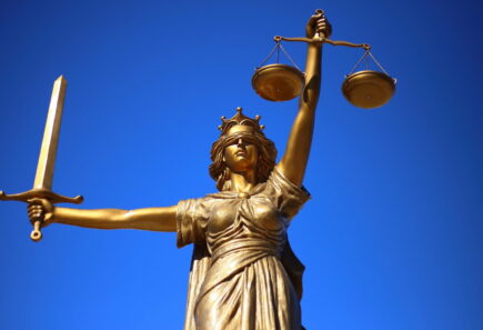 Bronze scales of justice with blue background