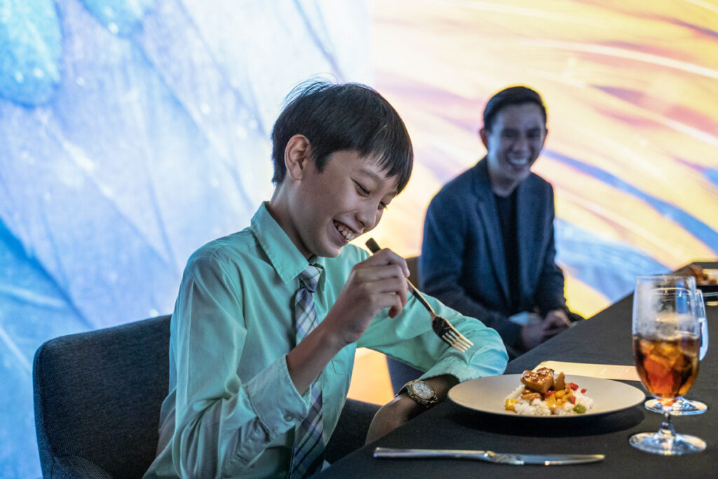 Year in review 2022 16 Boy eating food with person laughing behind