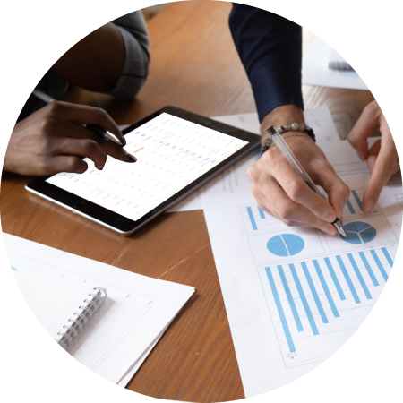 Two industry professionals work at a table while looking at a pie chart and tablet