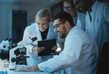 A team of scientists at a work station with a microscope