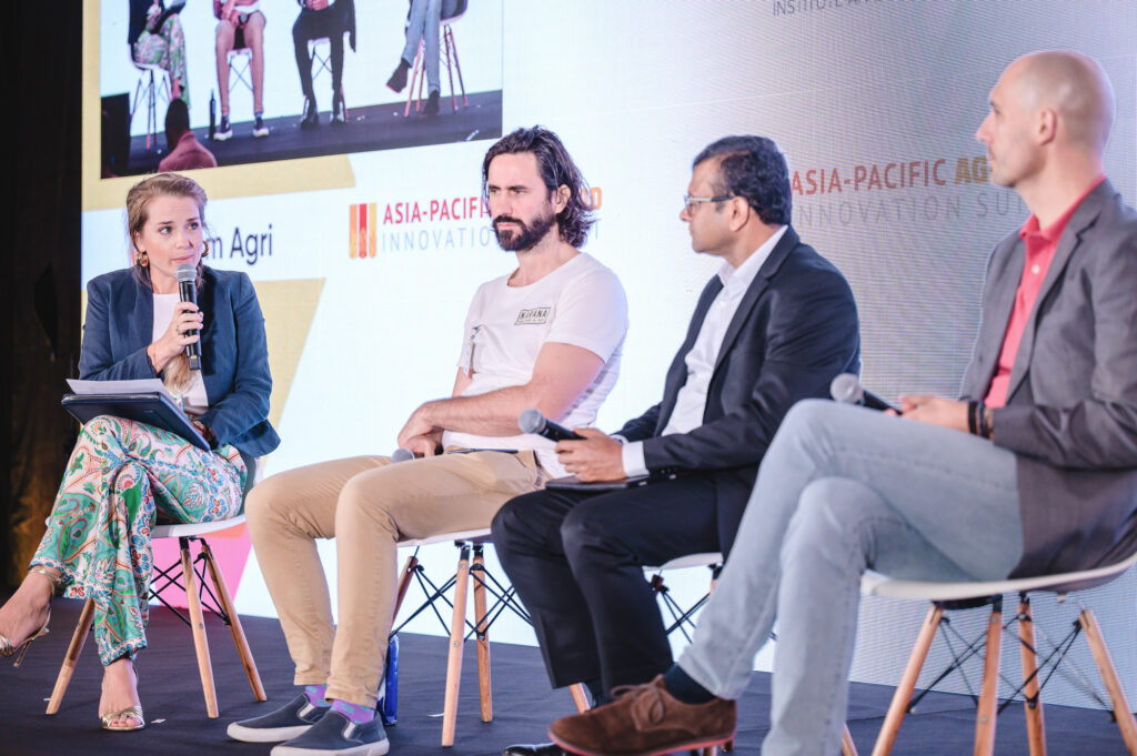 Four people sit in chairs on a stage. Mirte gosker (left) speaks into a microphone.
