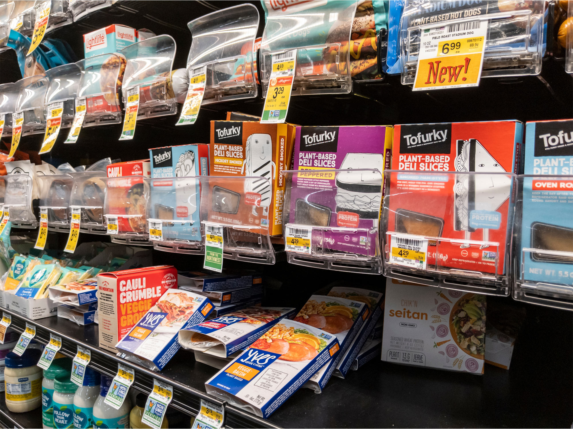 A grocery store shelf showing packages of tofurky brand products and other plant-based meat
