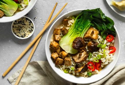 An overhead view of a dish with noodles, tofu, and bok choy